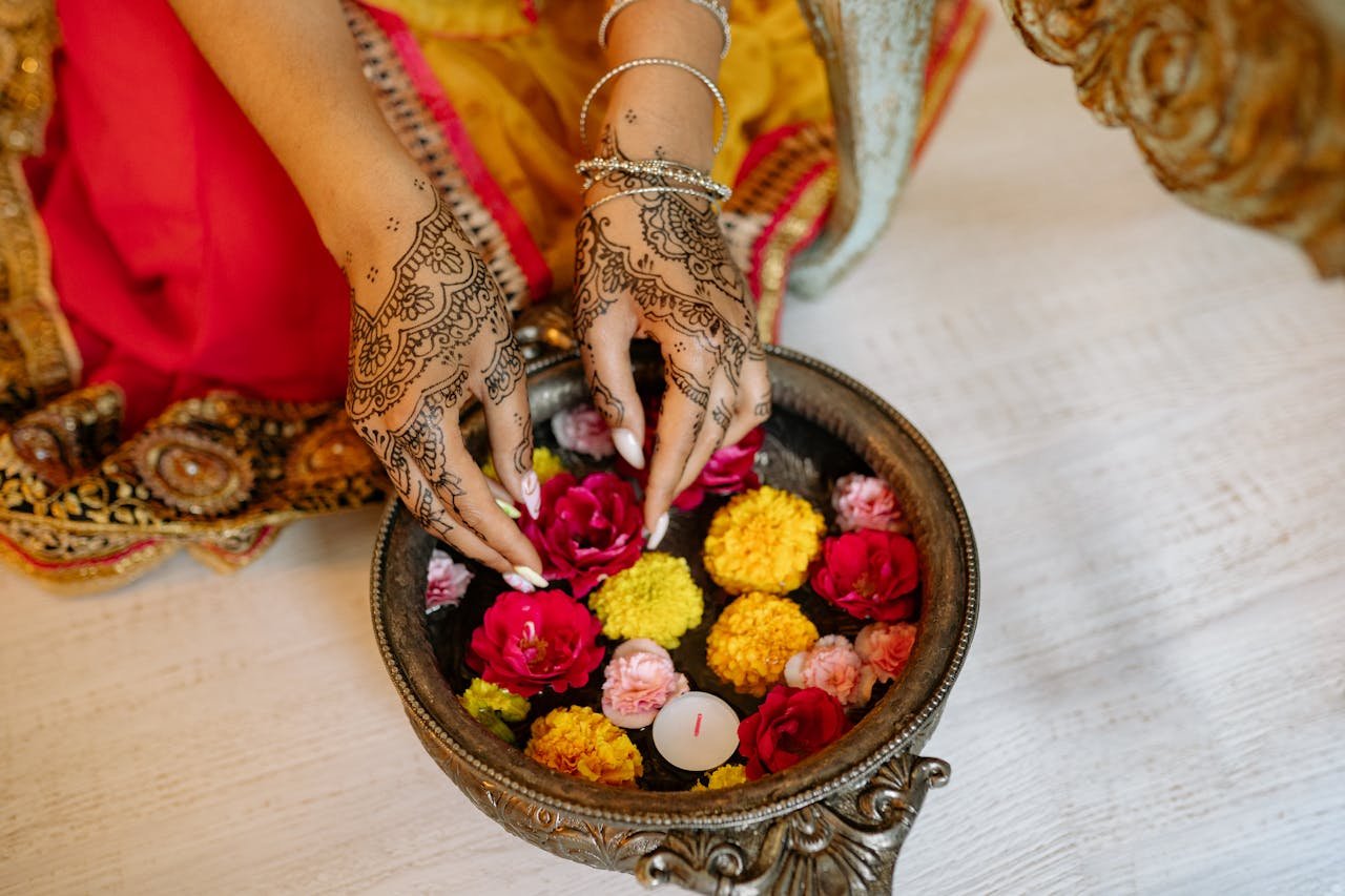 Hands with Mehndi Putting the Colorful Flowers on the Water
